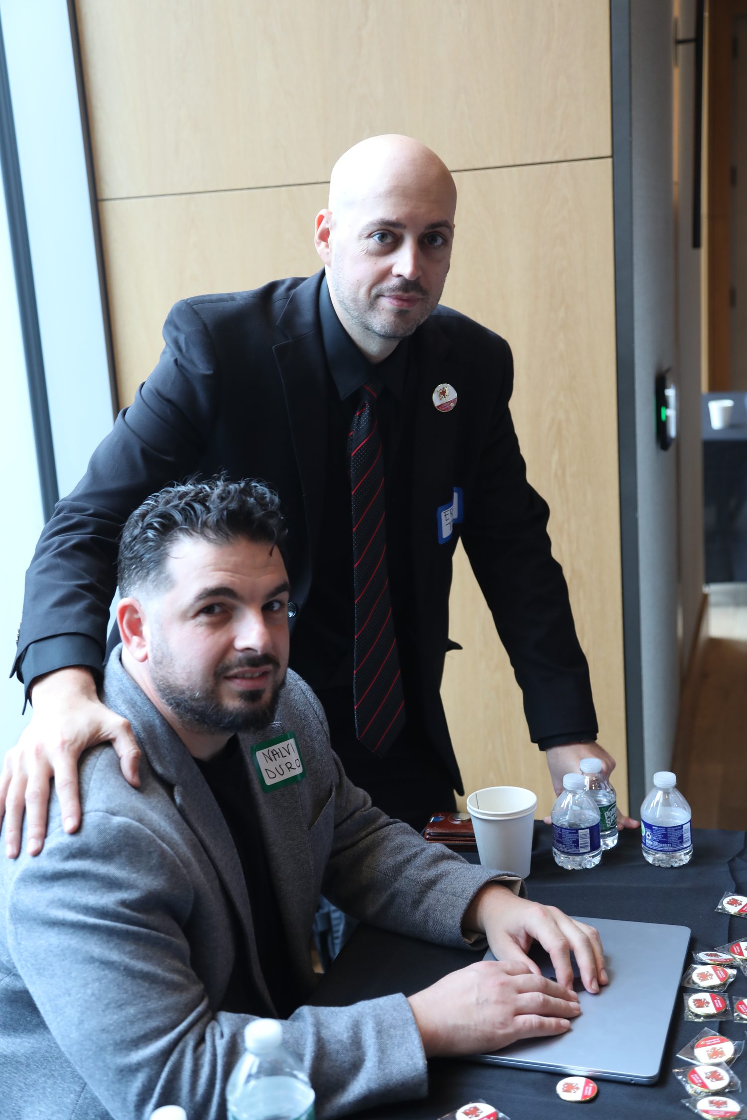 An organizer helping a colleague at the National Albanian Registry check-in table.