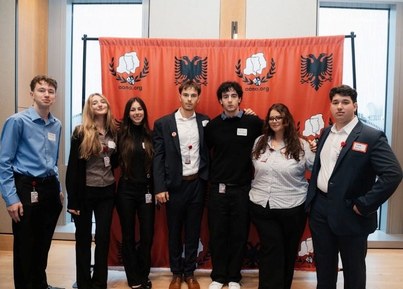 A group of students posing in front of the AANO backdrop.