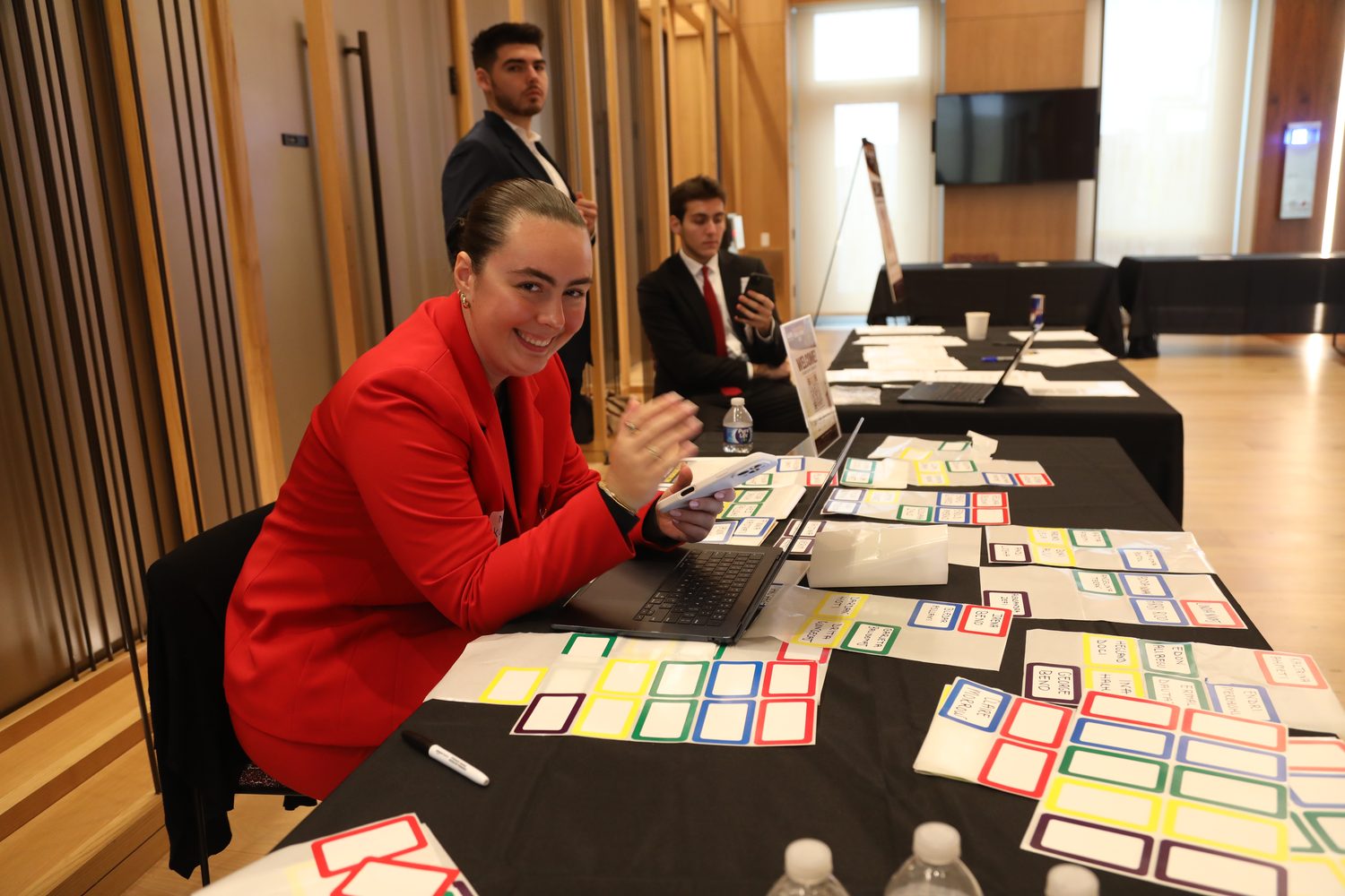 An organizer at the check-in table with printed name badges laid out in rows.