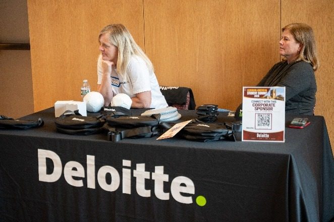 Deloitte representatives at their sponsor table with a corporate sponsor QR card.