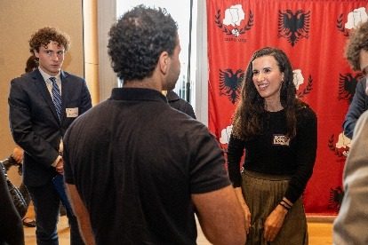 A professional talking with students in front of the AANO backdrop.