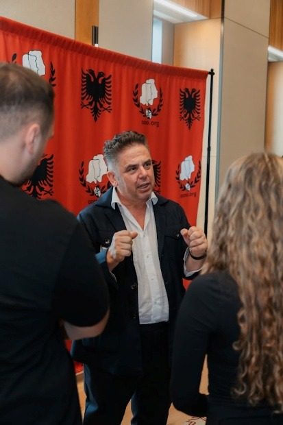 An attendee talking with two students beside the AANO backdrop.