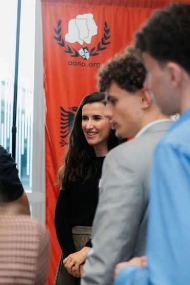 Students and professionals talking beside the AANO backdrop.