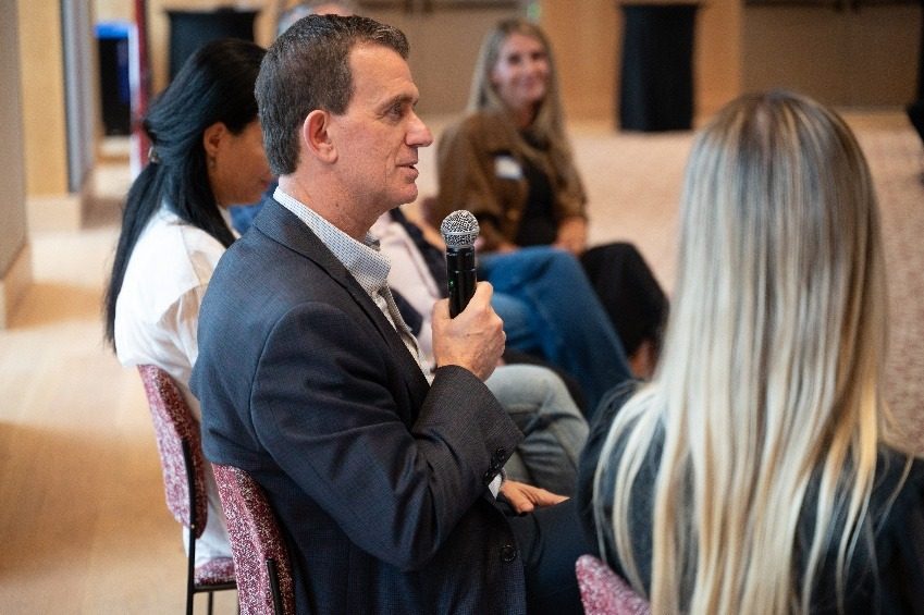 An attendee speaking into a microphone from the floor during the question period.