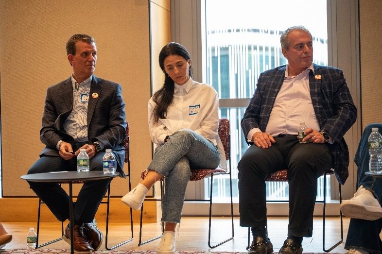 Three panelists seated on stage during a session.