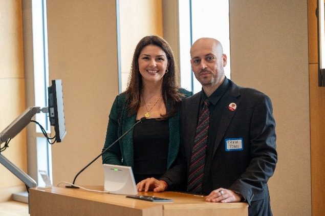 Two organizers beside the lectern at the front of the hall.