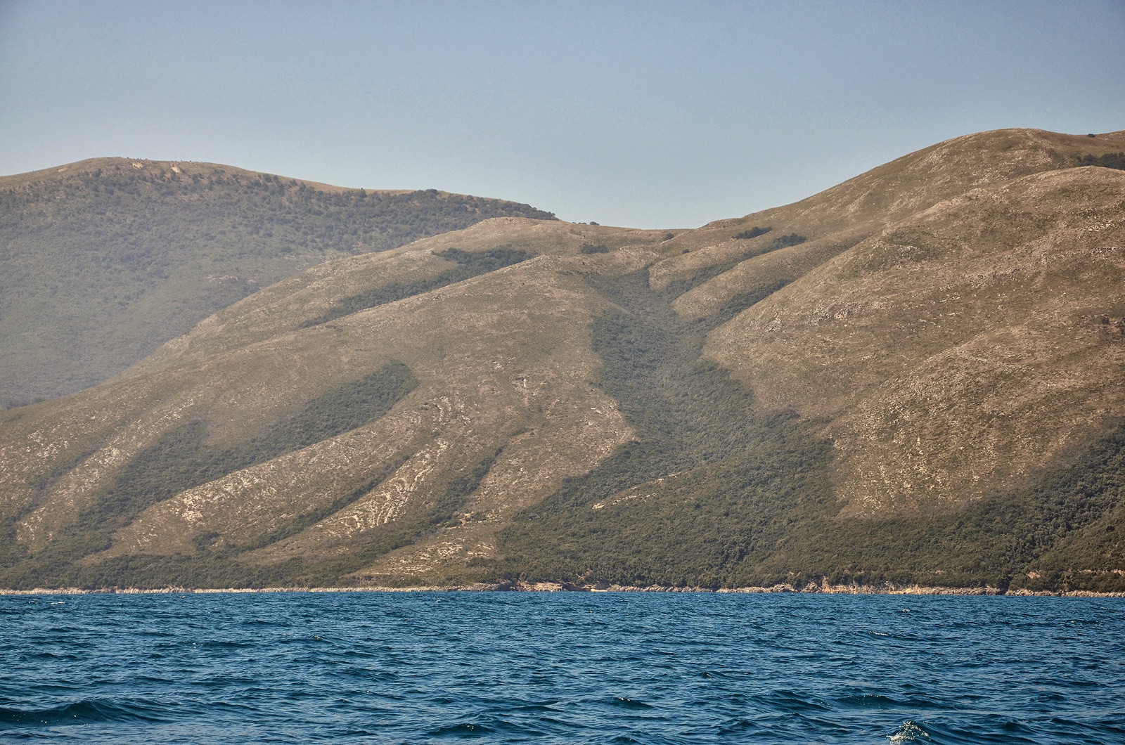 Gadishulli i Karaburunit i parë nga Gjiri i Vlorës — lloji i bregdetit të largët shqiptar i përdorur për zbarkimet e para me det.